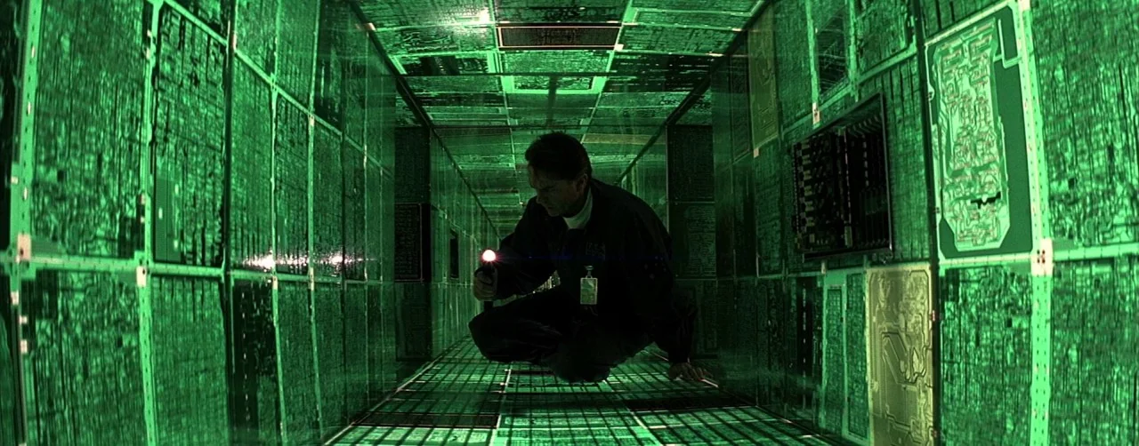 Event Horizon (1997) movie still: medium — A man kneels inside a narrow, futuristic corridor lined with glowing green circuit boards. He holds a…