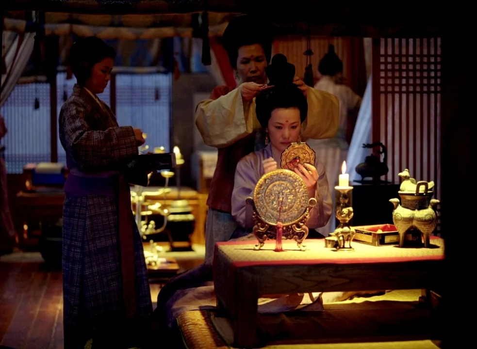 The Assassin (2015) movie still: medium — A dimly lit room features traditional wooden furniture, lattice screens, and warm candlelight. One woman…