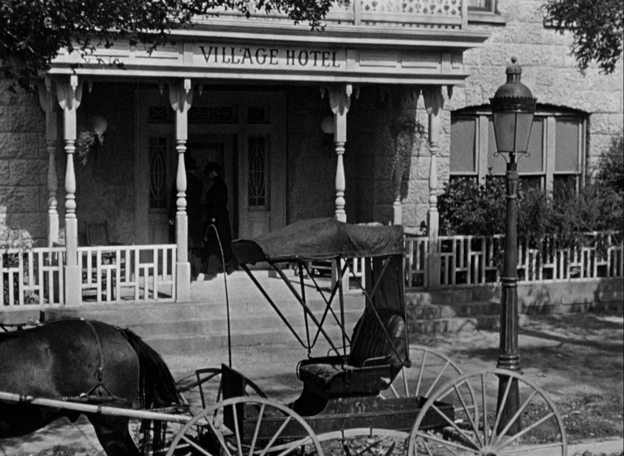 The Spiral Staircase (1946) movie still: wide — The exterior of a nineteenth-century village hotel features a wooden porch and veranda. A…