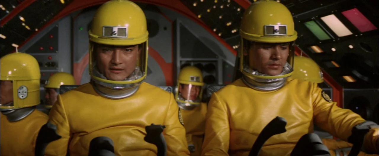Destroy All Monsters (1968) movie still: medium — The interior of a spaceship cockpit features a complex control panel with illuminated buttons.…