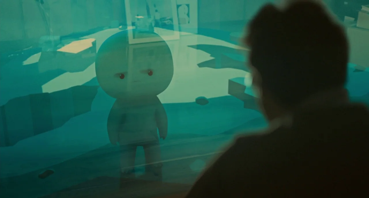 Her (2013) movie still: medium — A dimly lit room with a desk surface reflecting a vibrant cyan light. A small, stylized round-headed creature…
