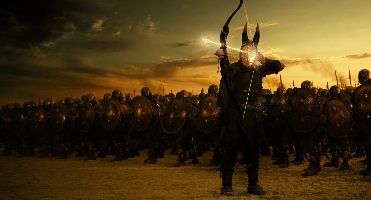 The Immortals (2011) movie still: wide — A vast army of armored warriors stands in formation on a desert plain. A central figure with a horned mask…
