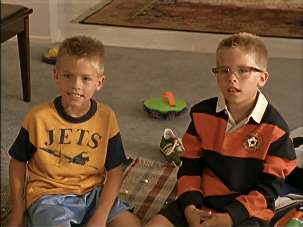 Just 4 Kicks (2003) movie still: medium — A carpeted room contains two young boys sitting on the floor together. The children look forward while…