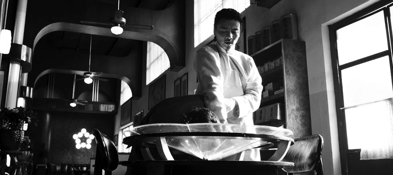 Master Z: The Ip Man Legacy (2018) movie still: medium — A vintage-style shop features dark wood, ceiling fans, and an ornate glass sink station. A…