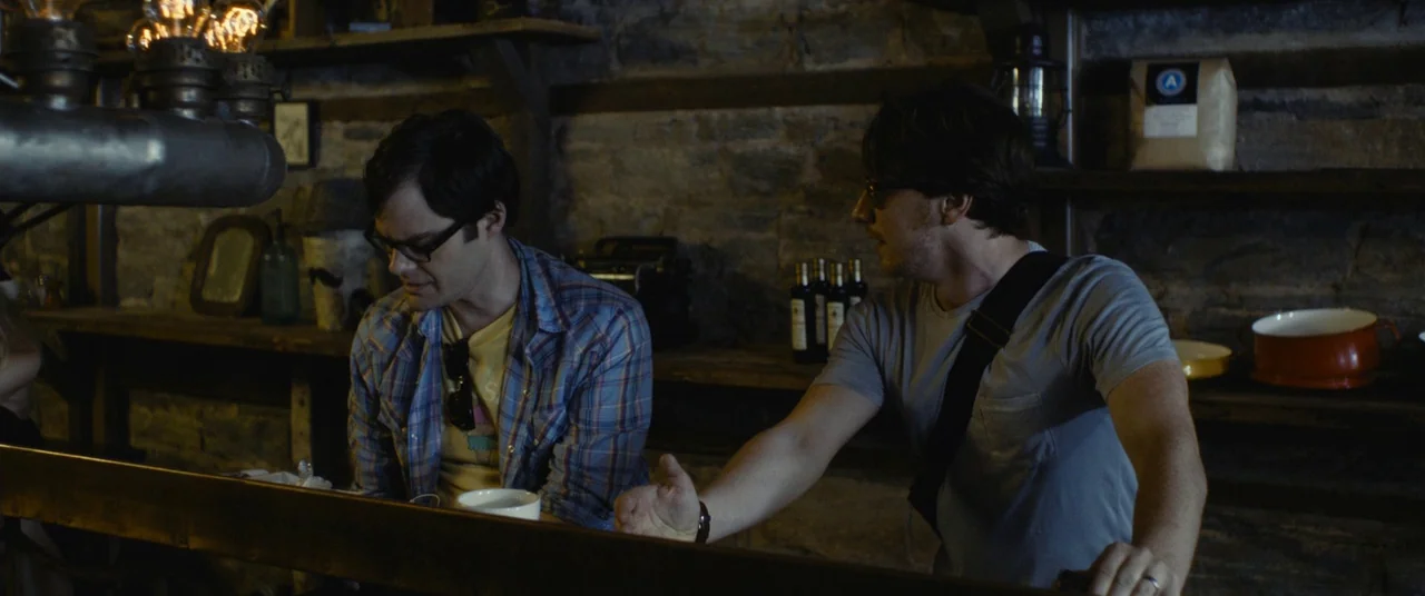 The Disappearance of Eleanor Rigby: Him (2014) movie still: medium — A dark stone-walled tavern space with rustic wooden shelves lining the back…