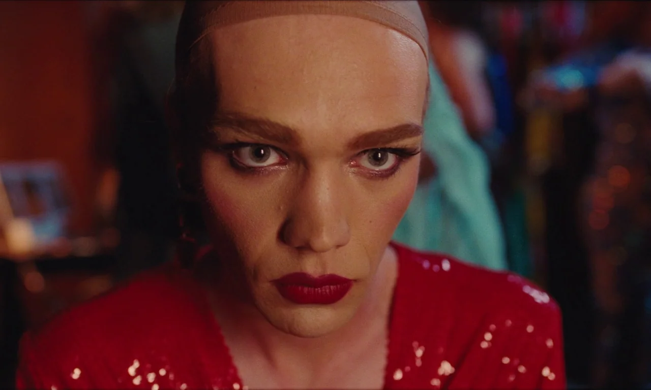 National Anthem (2023) movie still: closeup — A close-up shot focuses on a person wearing a red sequined garment. The subject, with makeup applied…