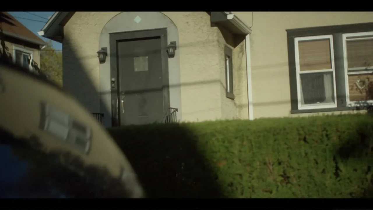 Diddy: The Making of a Bad Boy (2025) movie still: wide — A suburban home features light stucco siding and a prominent dark front door. A foreground…