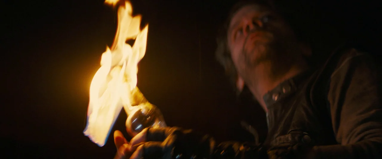 Don’t Breathe 2 (2021) movie still: medium — A dark environment surrounds a man holding an ignited torch against the blackness. He stands in the…