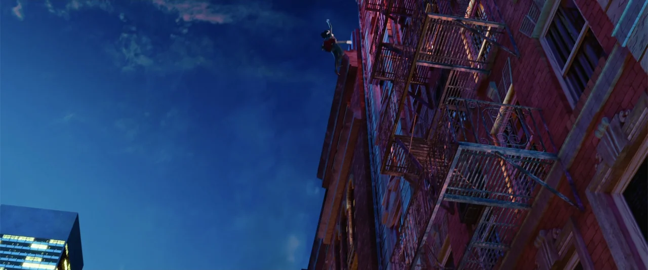 Happy Family (2018) movie still: wide — A tall urban brick building features a metal fire escape on the side. A lone figure stands on the top edge…