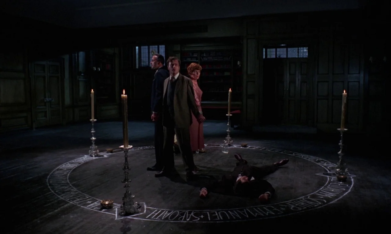 The Devil Rides Out (1968) movie still: fullbody — A dark, wood-paneled library with a chalk-drawn occult circle on the hardwood floor. Three…