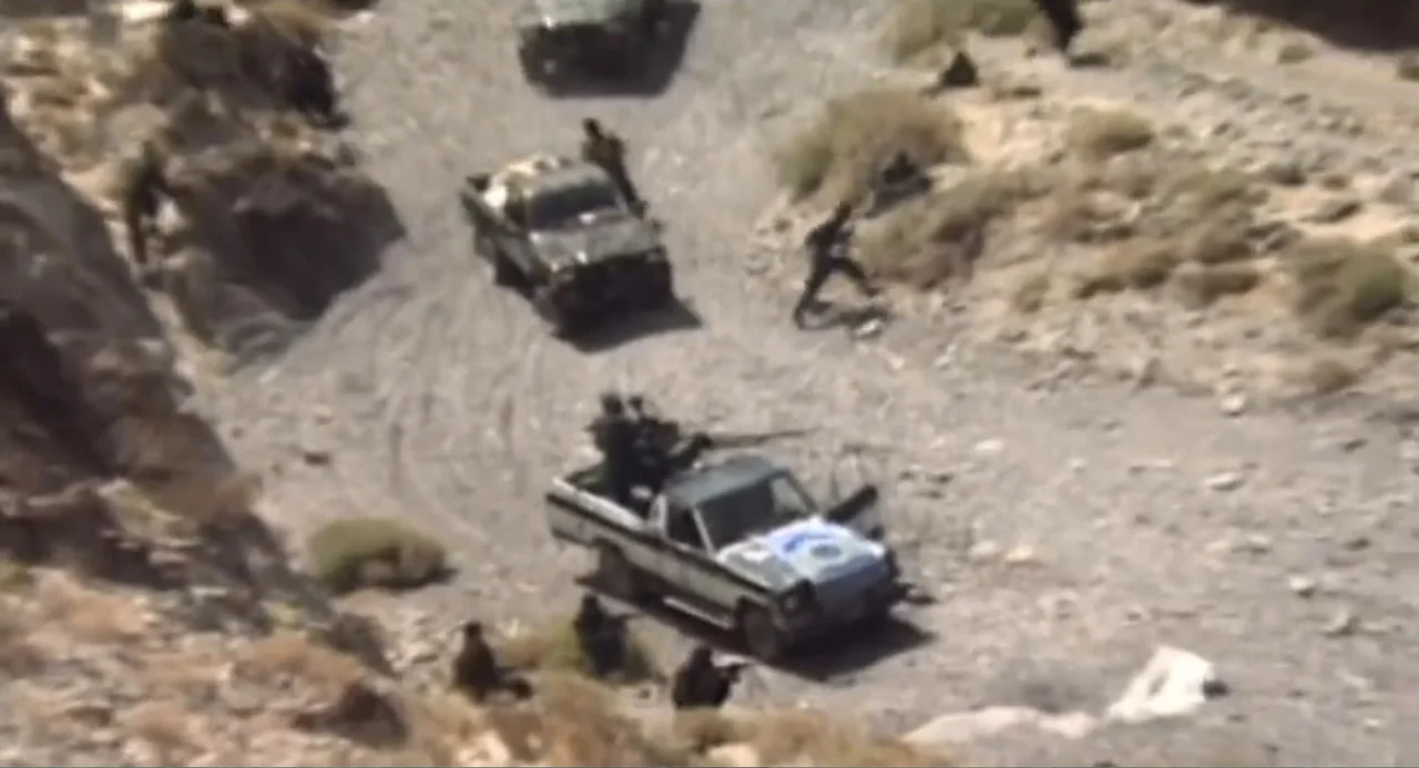 Afghanistan's Opium Trail (2007) movie still: wide — A dry mountain canyon with rocky slopes and a dirt track floor. Armed men in tactical gear…