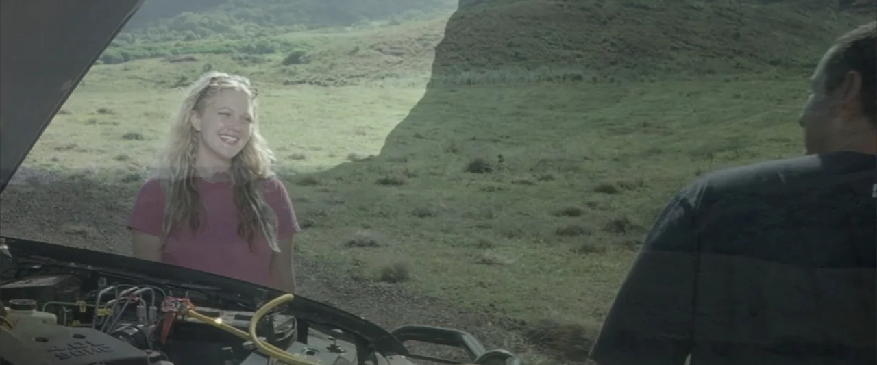 50 First Dates (2004) movie still: medium — A grassy meadow landscape sits under an overcast sky with a vehicle parked foreground. A blonde woman…
