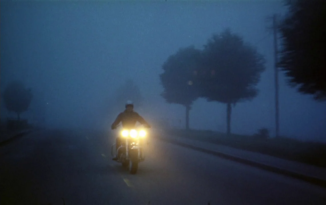 The Girl on a Motorcycle (1968) movie still: wide — A motorcyclist travels down a rural road surrounded by thick, low-lying nocturnal fog.…