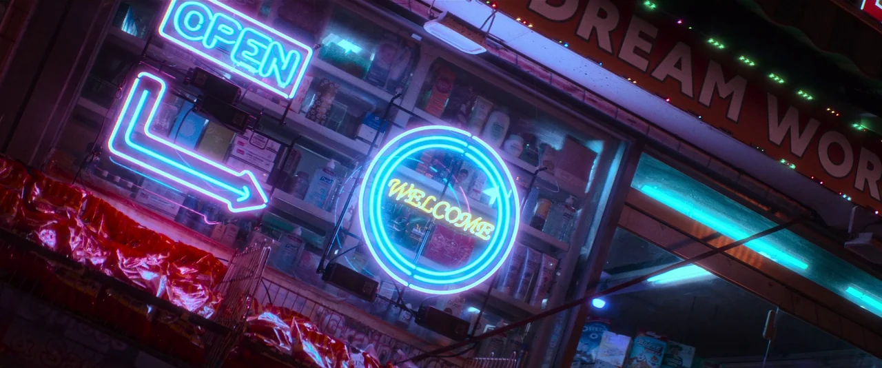 Ballerina (2023) movie still: establishing — The exterior storefront displays bright neon signs against shelves filled with retail merchandise. A…