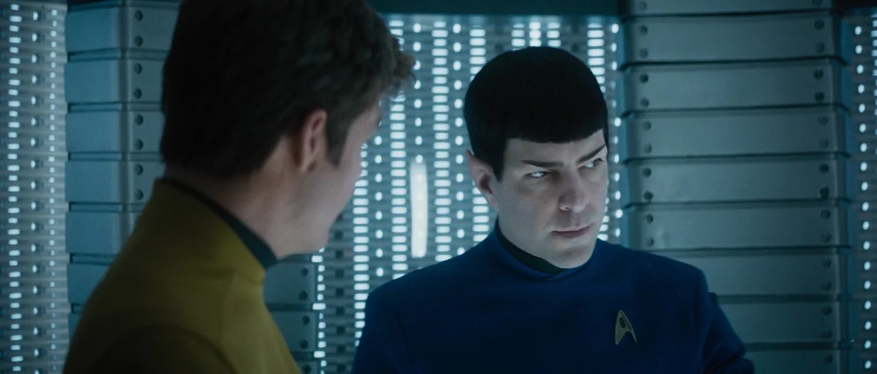Star Trek Beyond (2016) movie still: medium — A high-tech interior space with stacked modular storage units and a metallic wall grate. Two men in…