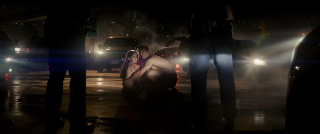 Terminator Genisys (2015) movie still: medium — A dark highway at night with multiple vehicles stopped and bright headlights illuminated. A nude man…