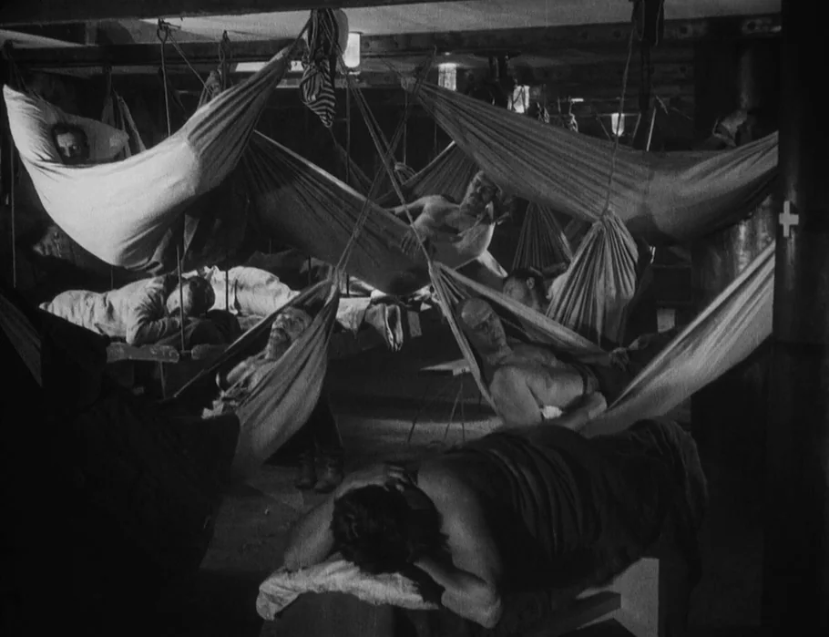 Battleship Potemkin (1925) movie still: wide — A cramped, low-ceilinged room on a ship filled with many canvas hammocks. Several men lie in the…