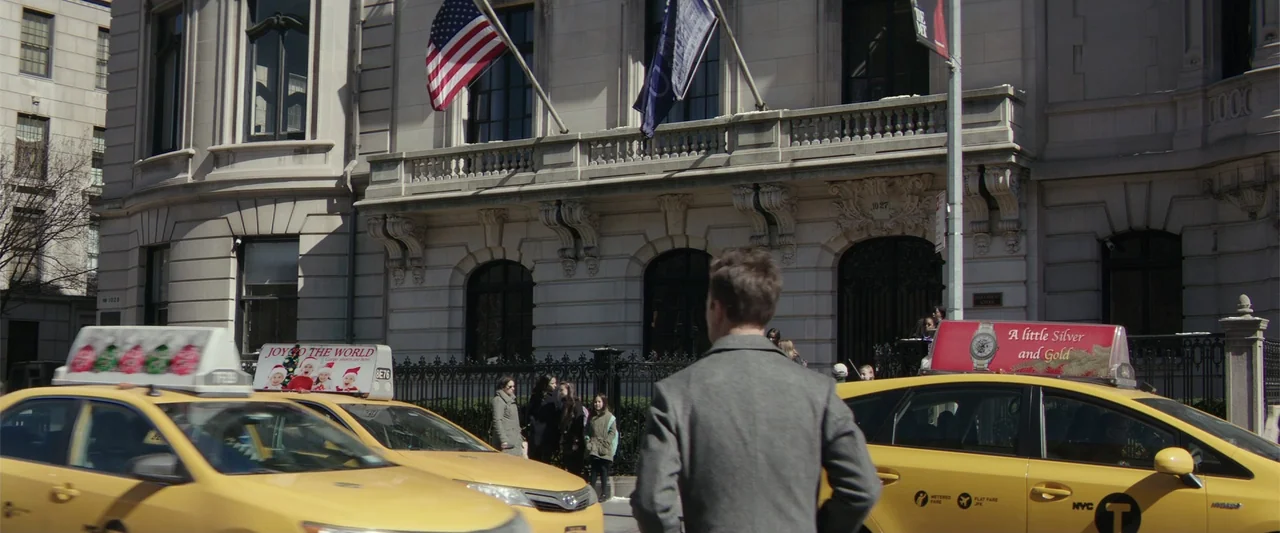 Collateral Beauty (2016) movie still: medium — A man stands on a New York City sidewalk near a classic stone building. The man in a grey coat faces…