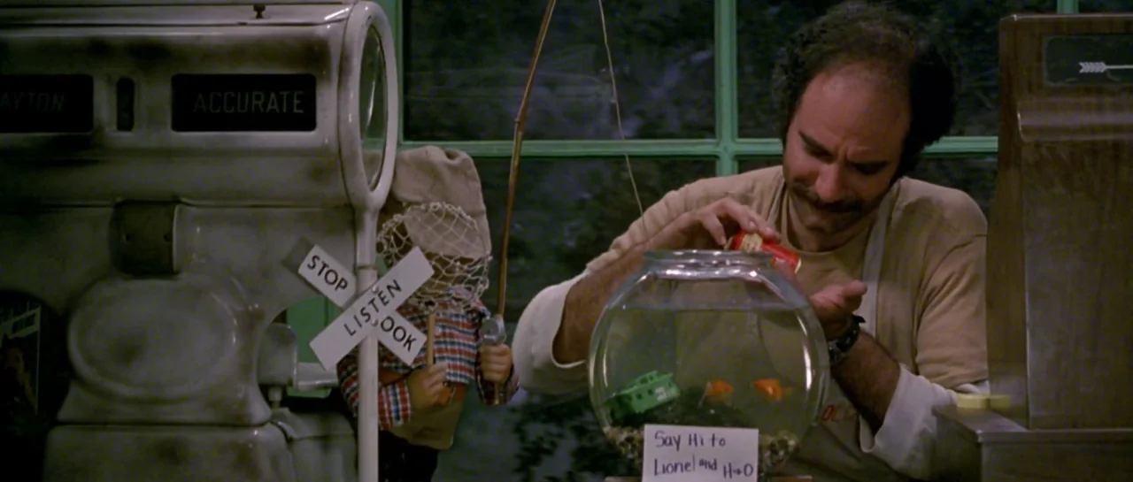 Friday the 13th Part III (1982) movie still: medium — A cluttered shop counter features a vintage scale and a toy train car. The shopkeeper feeds…