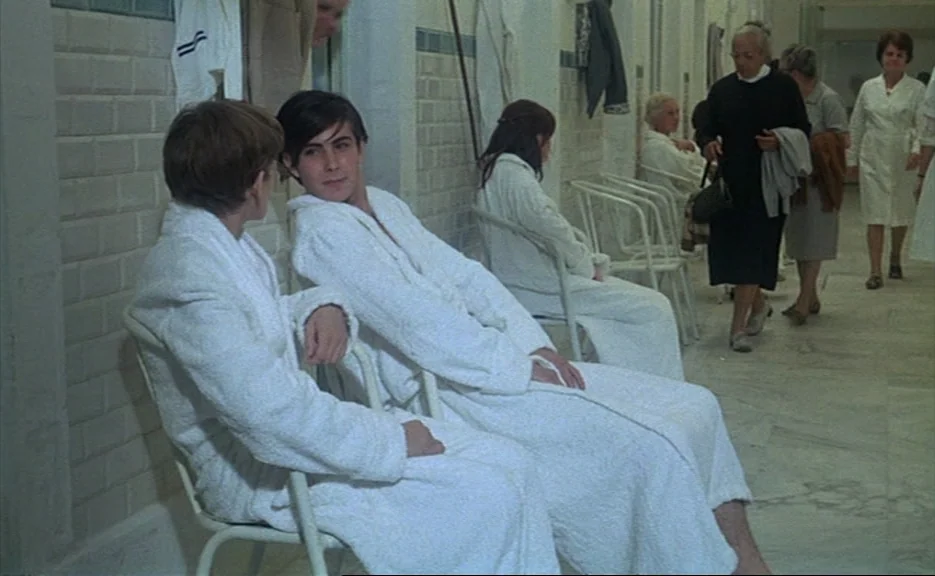 Murmur of the Heart (1971) movie still: medium — A long institutional hallway with light-colored tile walls and marble-style flooring.