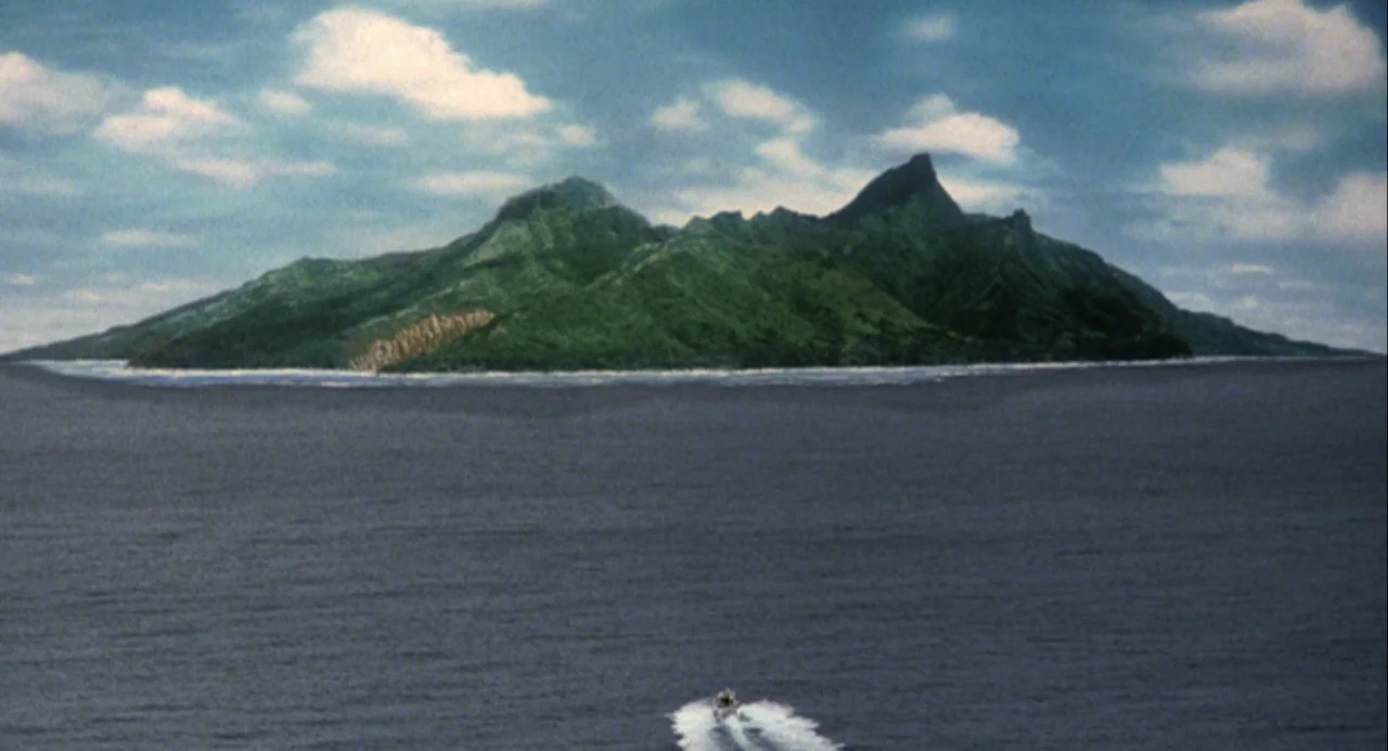 Godzilla and Mothra: The Battle for Earth (1992) movie still: establishing — A remote volcanic island rises out of deep blue ocean waters under a…