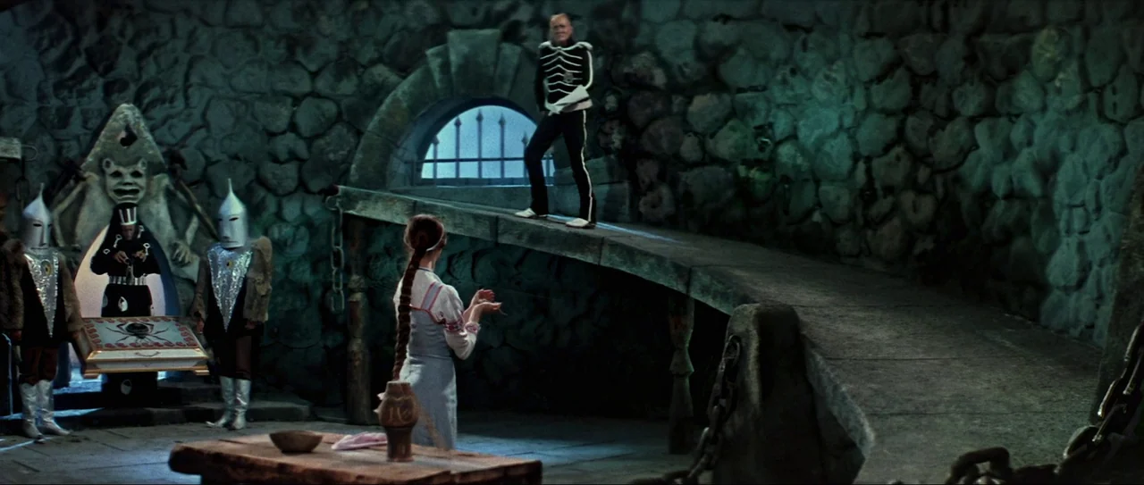 Through Fire, Water and… Brass Pipes (1968) movie still: wide — A stone chamber with curved walls features a raised masonry ramp and a barred…