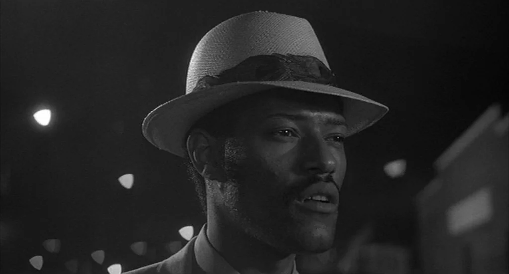 Rumble Fish (1983) movie still: closeup — A man stands outdoors at night under soft, dim illumination. He turns his head while looking toward the…