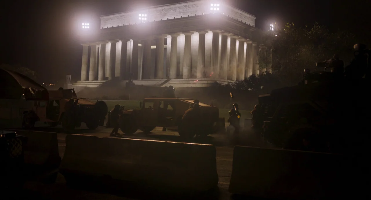 Civil War (2024) movie still: wide — A massive white neoclassical monument is illuminated at night by several high-intensity floodlights. Several…