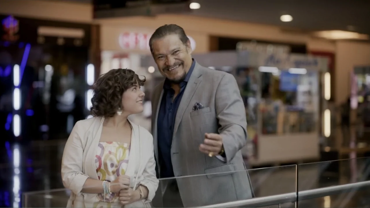 Lecciones para canallas (2022) movie still: medium — A modern, multi-level shopping center with blurred storefronts and glass railings in the…