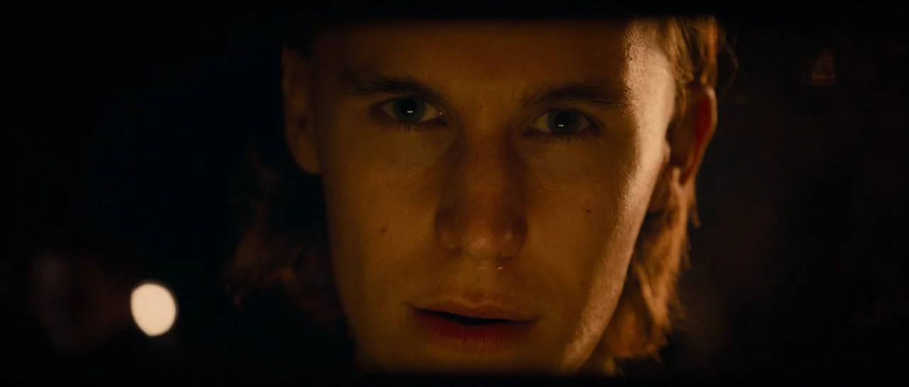 The Purge (2013) movie still: closeup — The interior of a dark car at night frames the subject's face centrally. A low-intensity light source from…