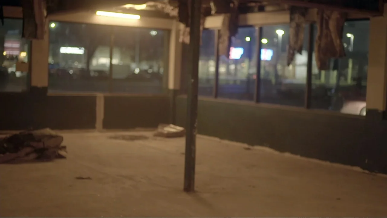Murders at the Burger Joint (2022) movie still: establishing — An abandoned commercial space features large windows looking out onto a dark street…