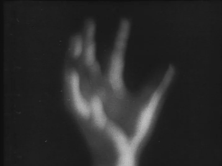 Making of: The Wheel (La Roue) (1923) movie still: closeup — A blurry, glowing hand shape floats against a deep black void. No other physical…