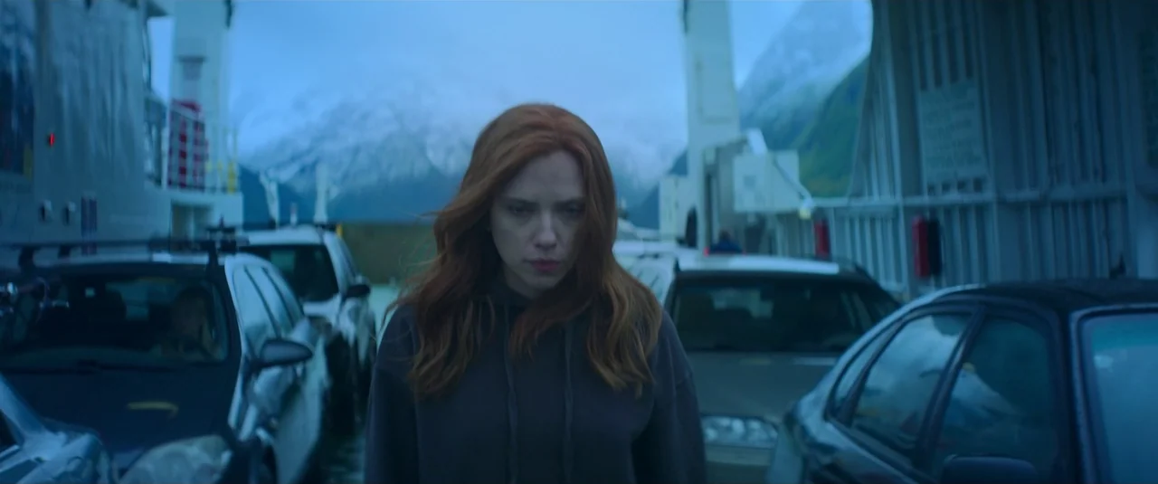 Black Widow (2021) movie still: medium — A vehicle deck on a ferry features parked cars and white structural railings. A woman with long auburn hair…