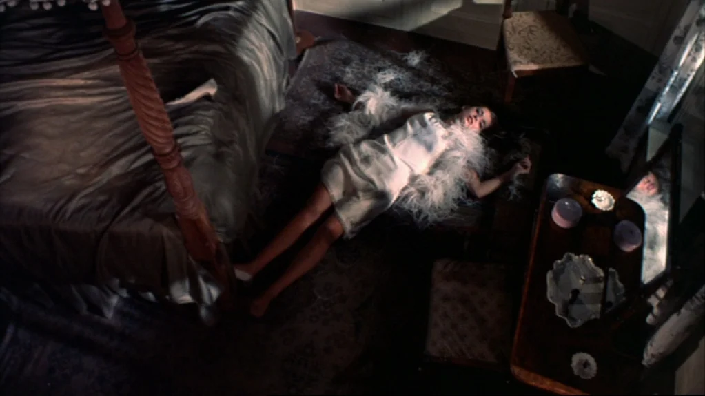 Accident (1967) movie still: wide — A furnished interior space with a patterned rug and wooden furniture under harsh light. A woman in a white dress…