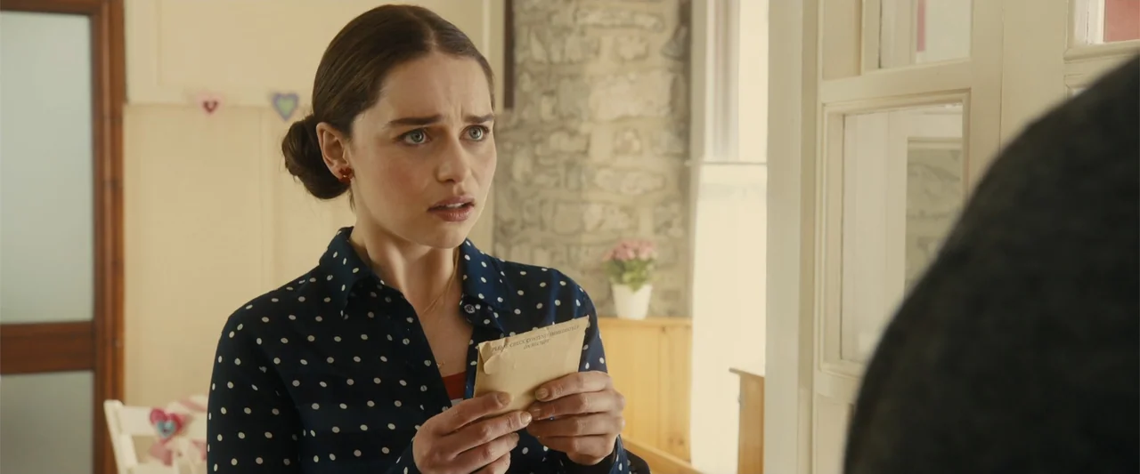 Me Before You (2016) movie still: medium — A residential room interior features a stone wall and a white window frame. A young woman holds a small…