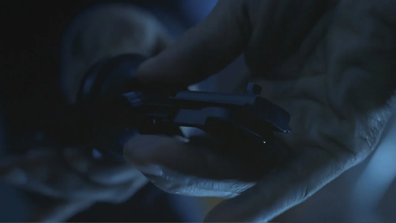 The Art of War (2000) movie still: closeup — An unidentified dimly lit interior space with shadows obscuring the background. A hand holds a small…