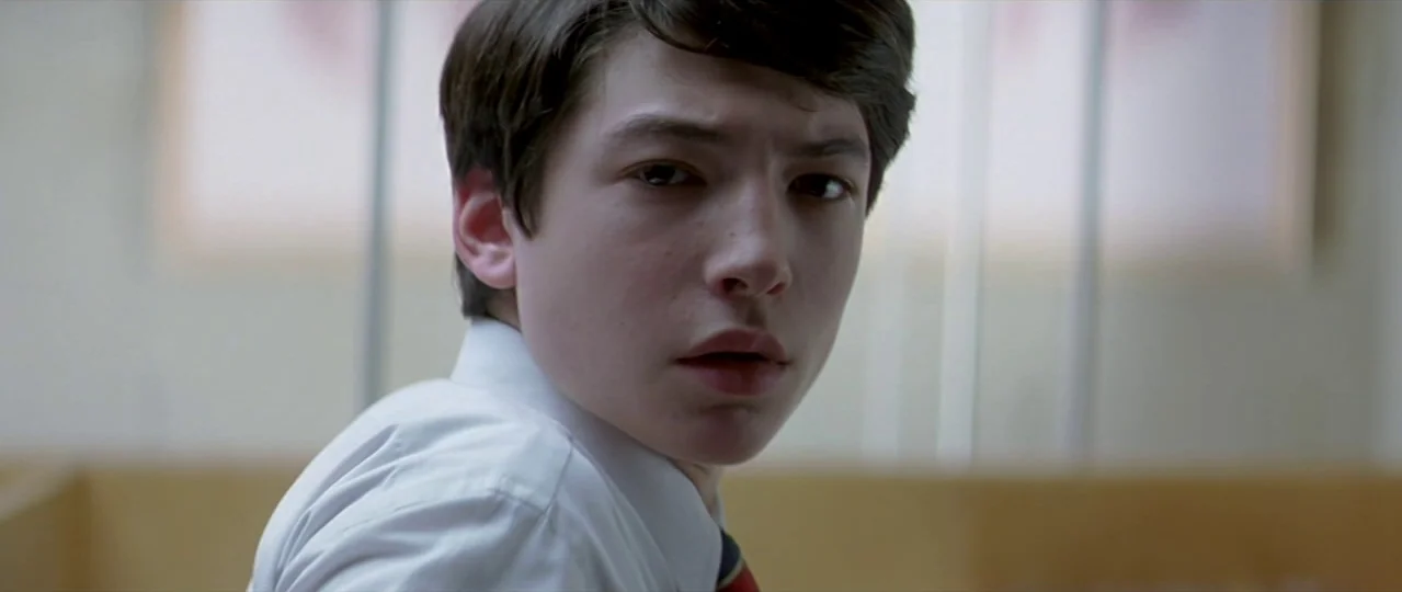 Afterschool (2008) movie still: closeup — An interior space features bright, neutral walls and soft, window-filtered daylight. A young man turns his…