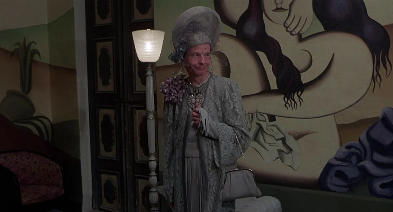 Salò, or the 120 Days of Sodom (1975) movie still: medium — A person stands in a corridor decorated with large, stylized, surrealist-inspired…
