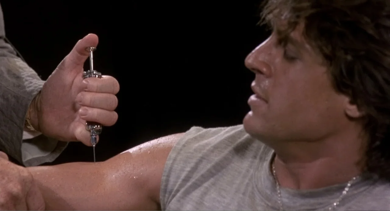 American Ninja 3: Blood Hunt (1989) movie still: medium — An interior space with black surroundings focuses on the muscular arm of a man. A hand…