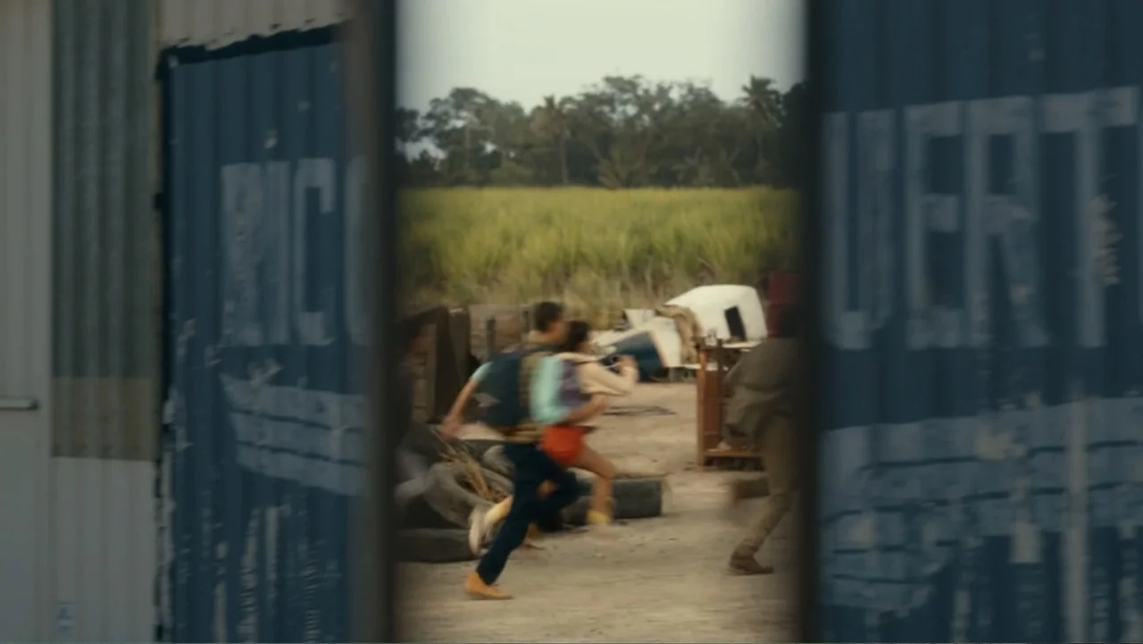 Dora and the Lost City of Gold (2019) movie still: medium — A dirt lot sits between large shipping containers with a rural background of fields.…