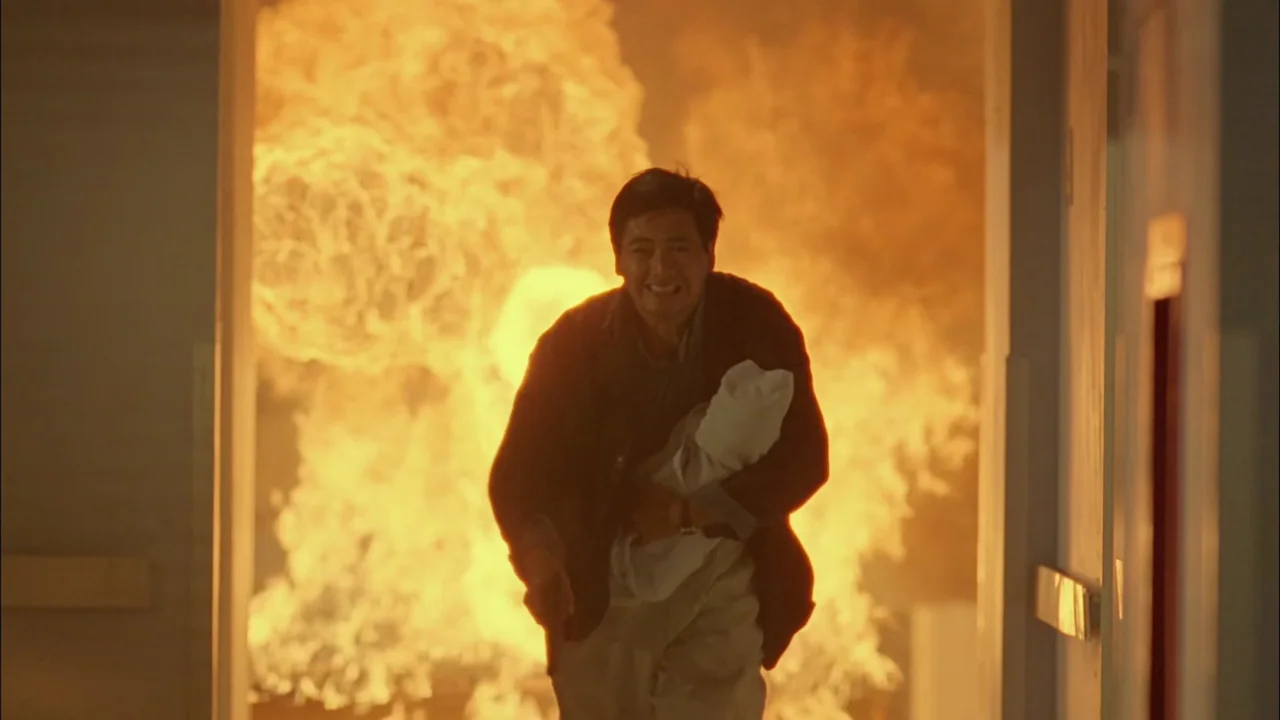 Hard Boiled (1992) movie still: medium — A man flees through a building corridor while a massive explosion erupts behind him. The environment is…