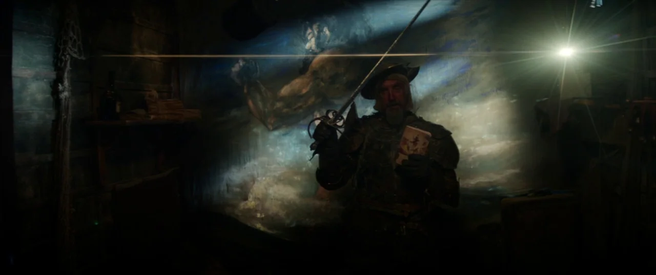 The Man Who Killed Don Quixote (2018) movie still: medium — A dark wooden room contains a large mural depicting a muscular figure on the wall. A man…