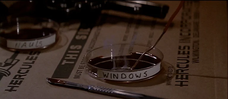 The Thing (1982) movie still: closeup — A close-up view of a laboratory bench covered in brown paper with medical supplies. A heated wire reacts…