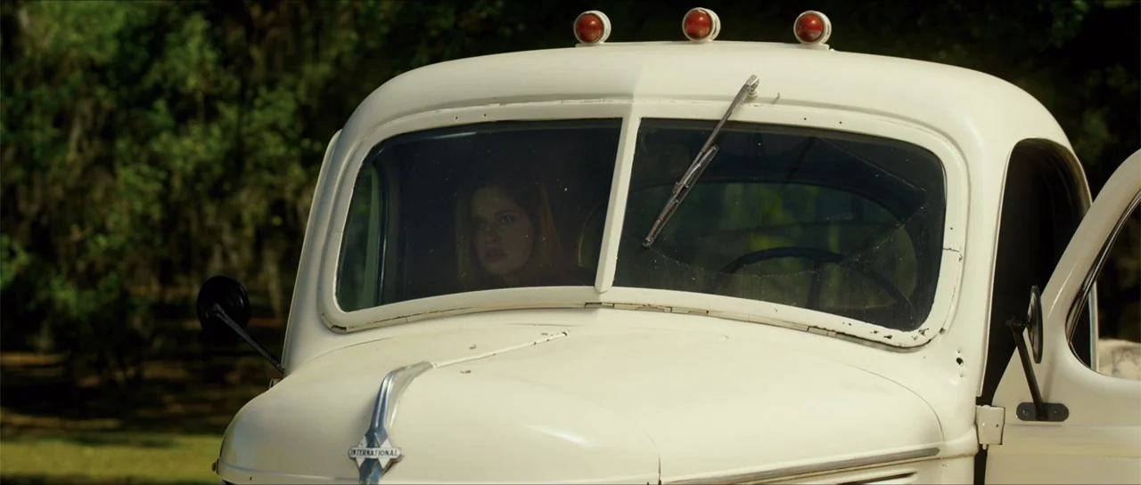 Jeepers Creepers 3 (2017) movie still: medium — A cream-colored vintage International truck sits outdoors with trees blurred in the background. A…
