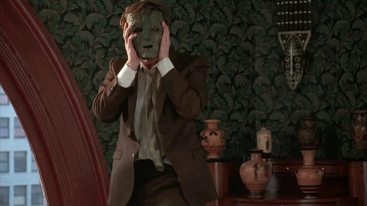 The Mask (1994) movie still: medium — An interior study features dark green leafy wallpaper and decorative terracotta style ceramic vases. A man…