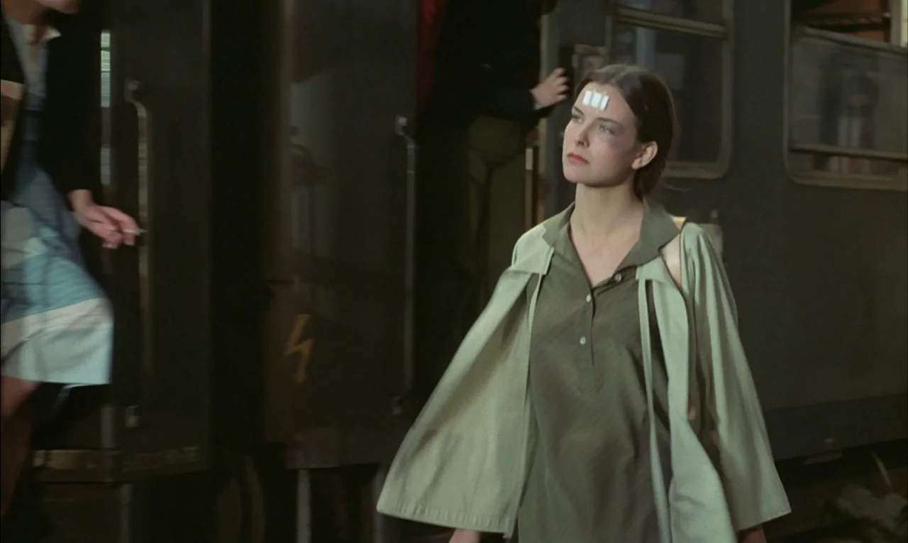 That Obscure Object of Desire (1977) movie still: medium — A dimly lit industrial rail platform features parked train cars in the background. A…
