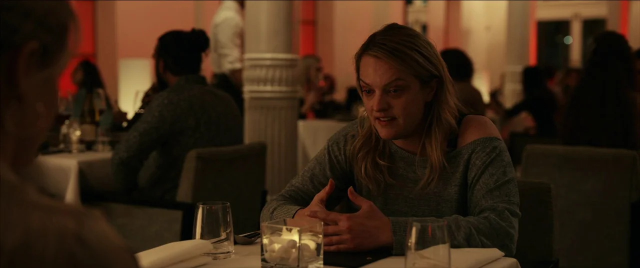 The Invisible Man (2020) (2020) movie still: medium — A dimly lit restaurant interior features white tablecloths and decorative glass table cubes. A…