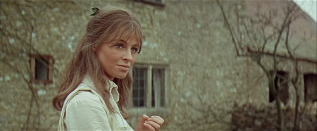 Far from the Madding Crowd (1967) movie still: medium — An old stone building stands in the background on a rural property. A woman with long brown…