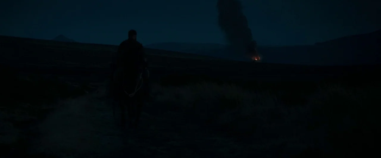 Black ’47 (2018) movie still: wide — A dark, expansive grassy field stretches out under a night sky. A lone rider on horseback travels towards a…