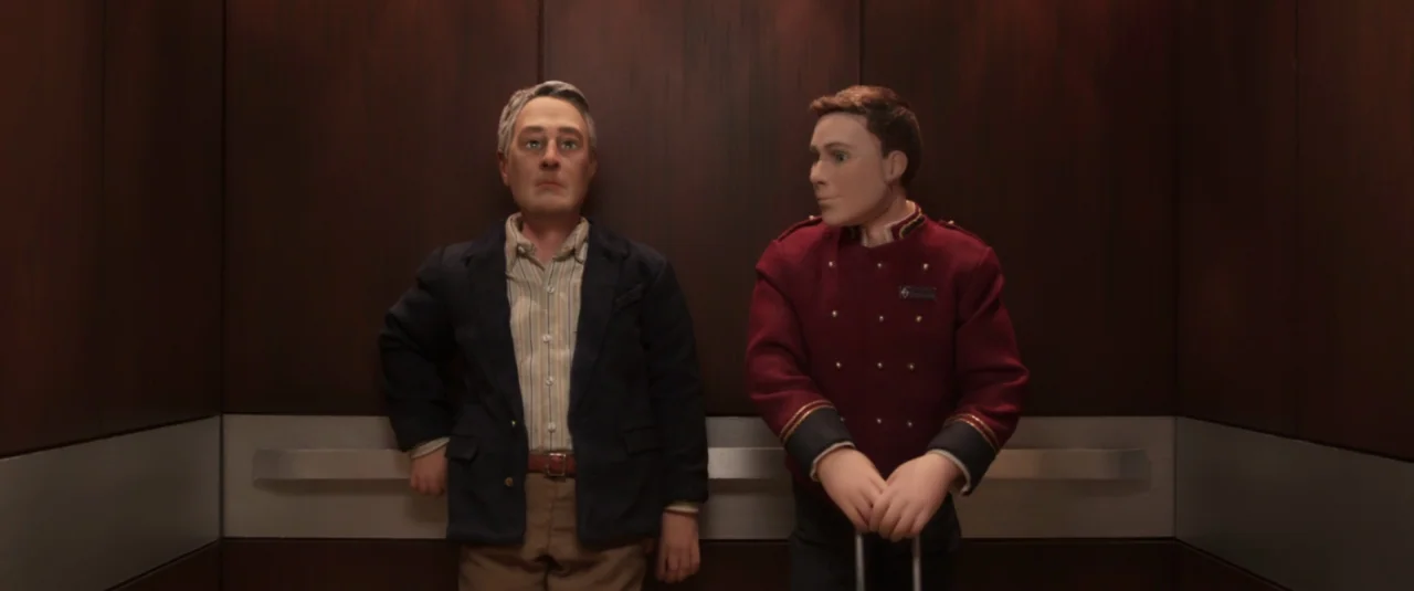 Anomalisa (2015) movie still: medium — An elevator interior lined with dark mahogany wood panels and silver horizontal trim. A mature man in a…